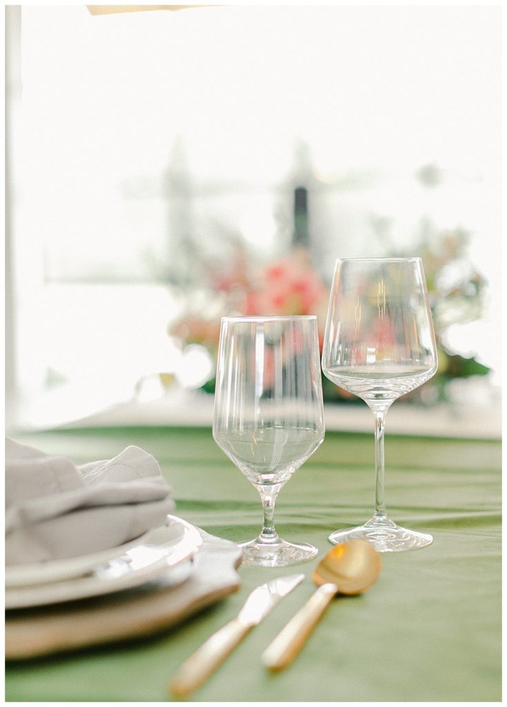 wine glasses on green tablecloth with goldware