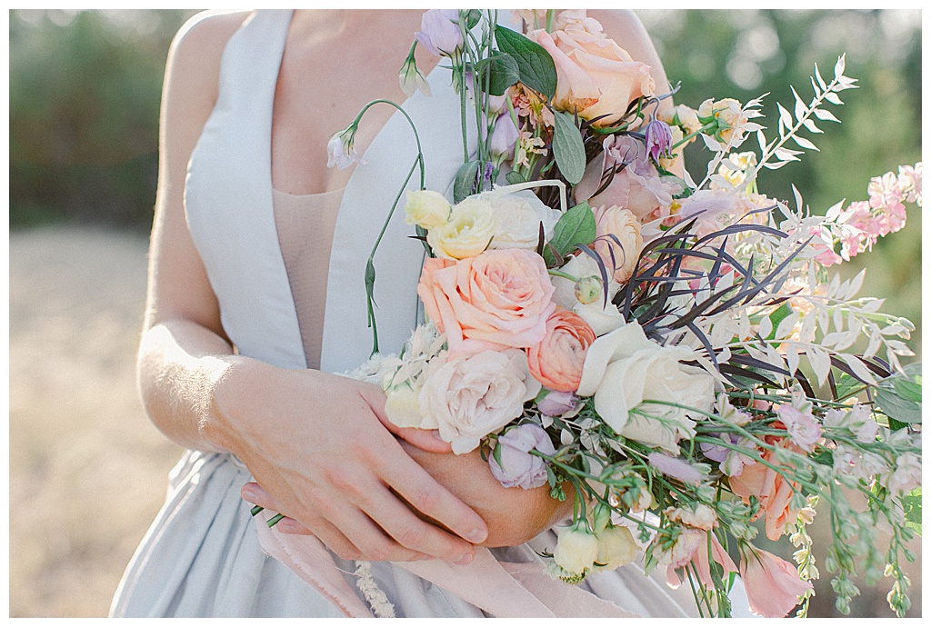 cropped photo of bride holding pastel wedding bouquet