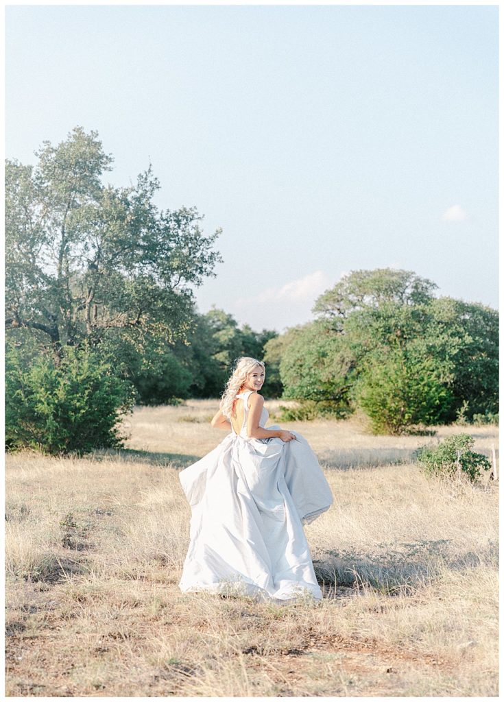 bride holding dress running through texas countryside