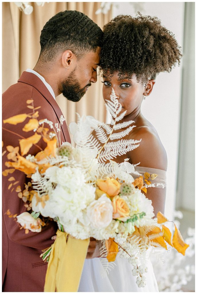 Couple embracing while holding earth tones bouquet