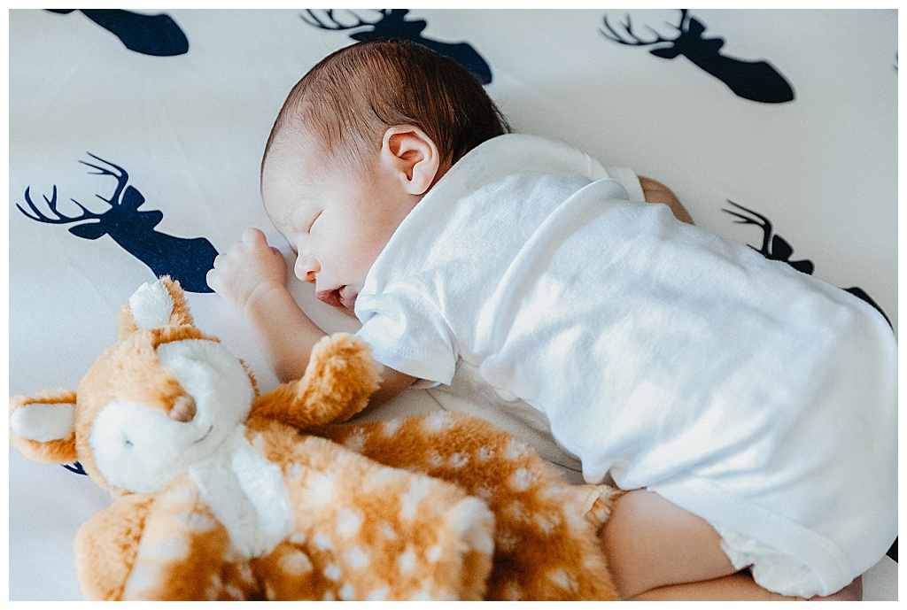 newborn baby sleeping on sheets with deer on them