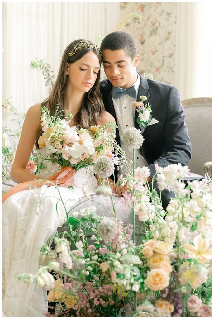 Wedding couple sitting together surrounded with spring floral arrangements