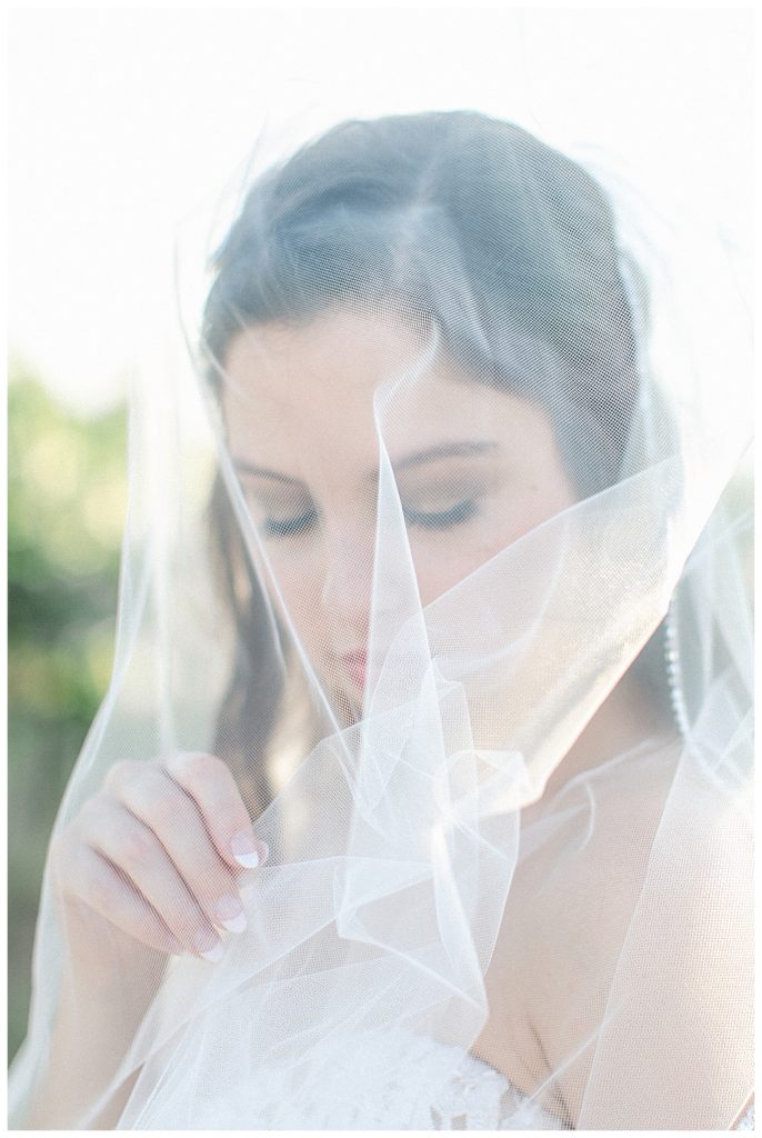 bride holding veil while looking down