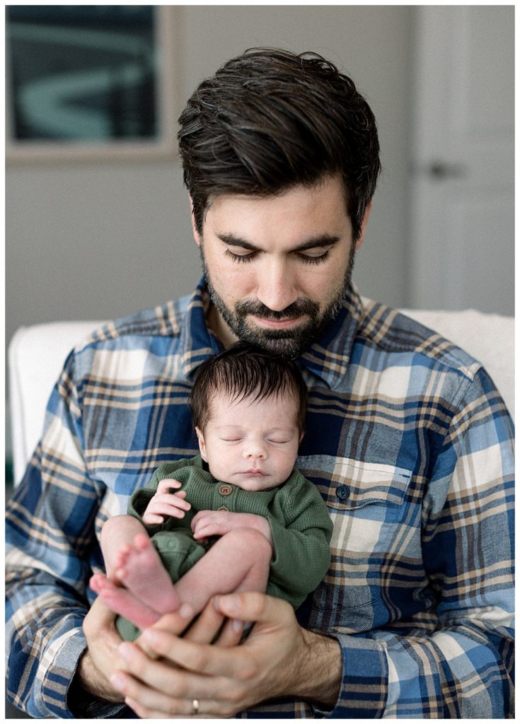 dad holding newborn baby below his chin