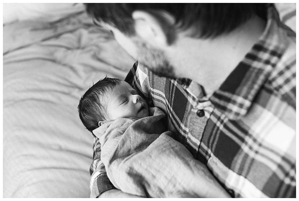 black and white photo of dad looking down at newborn