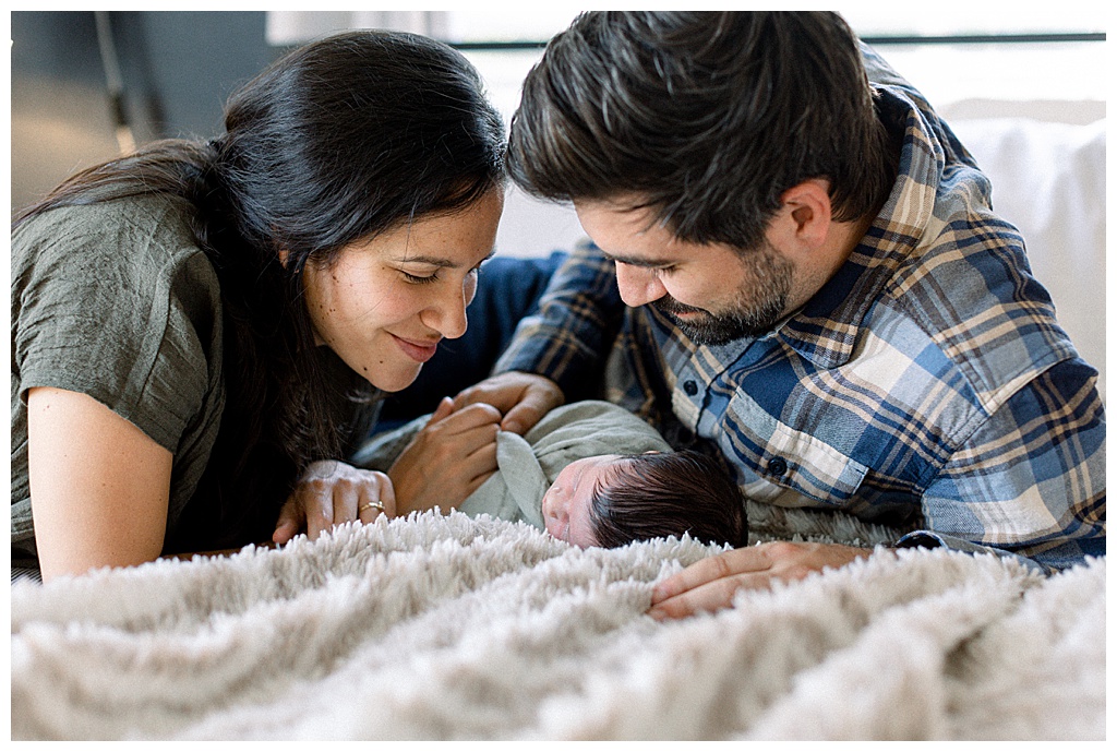 new parents smiling at new baby in bed