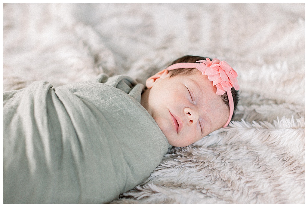 newborn baby girl wrapped in sage blanket