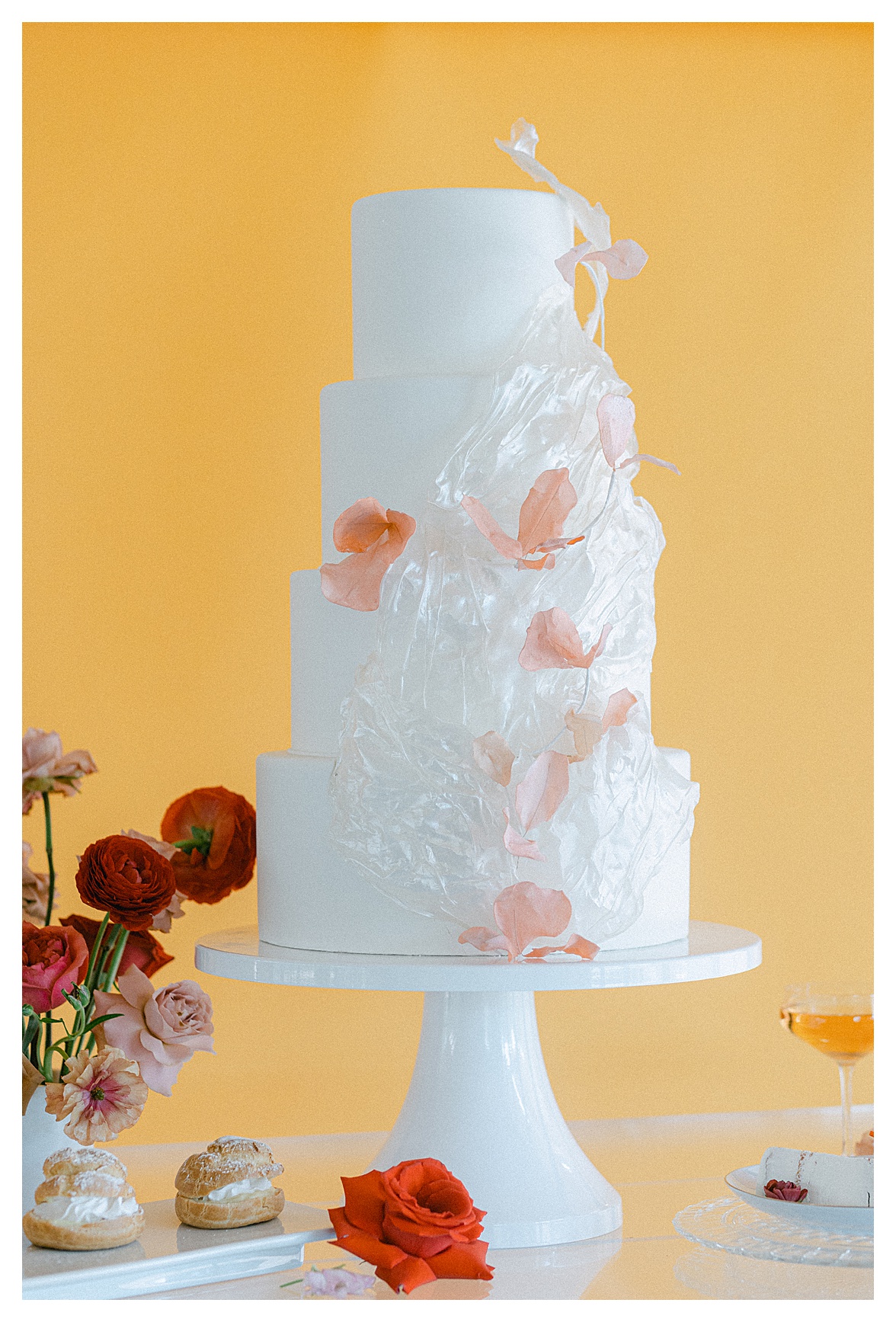 four tiered wedding cake with bright yellow backdrop
