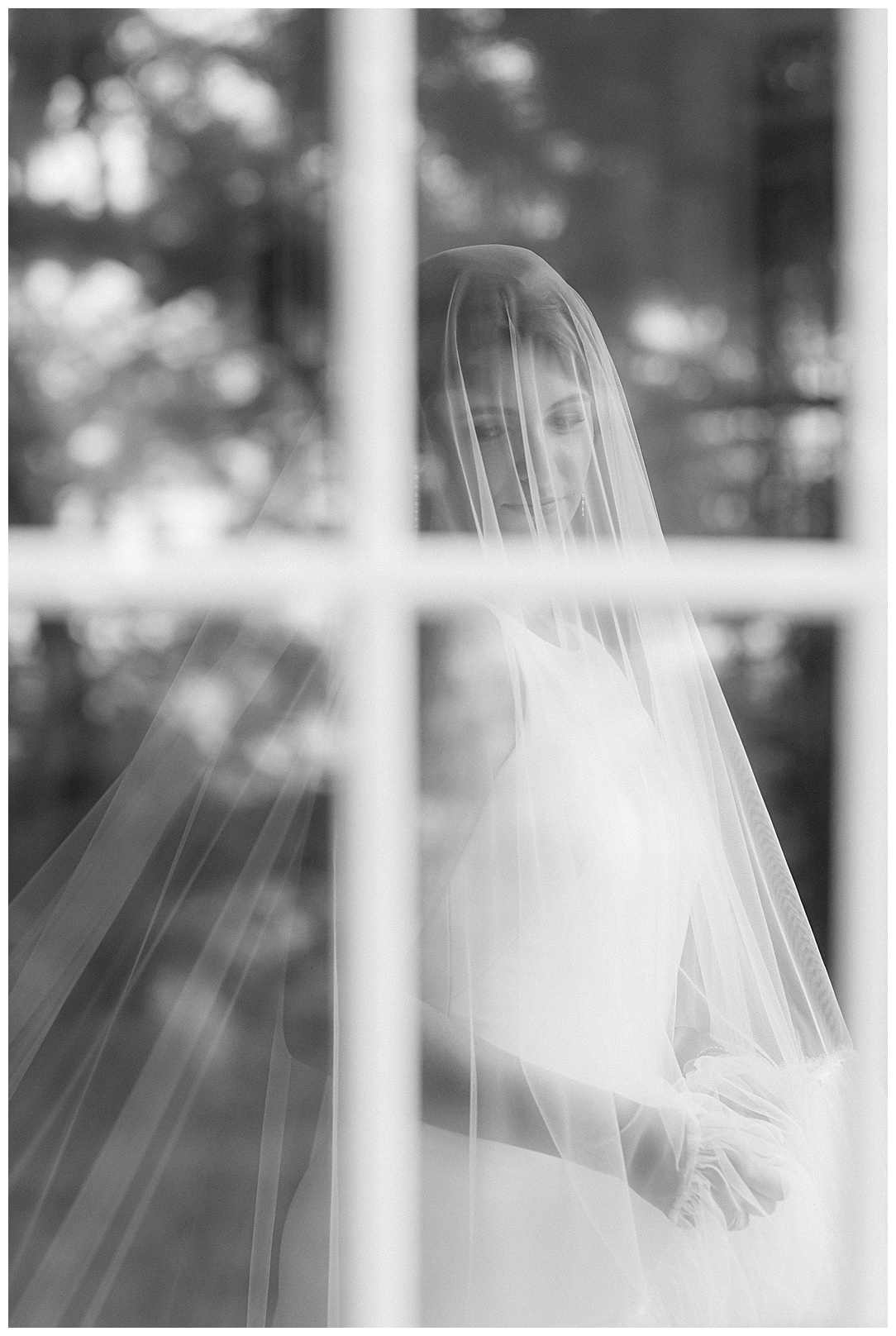 black and white portrait of bride shot through glass window