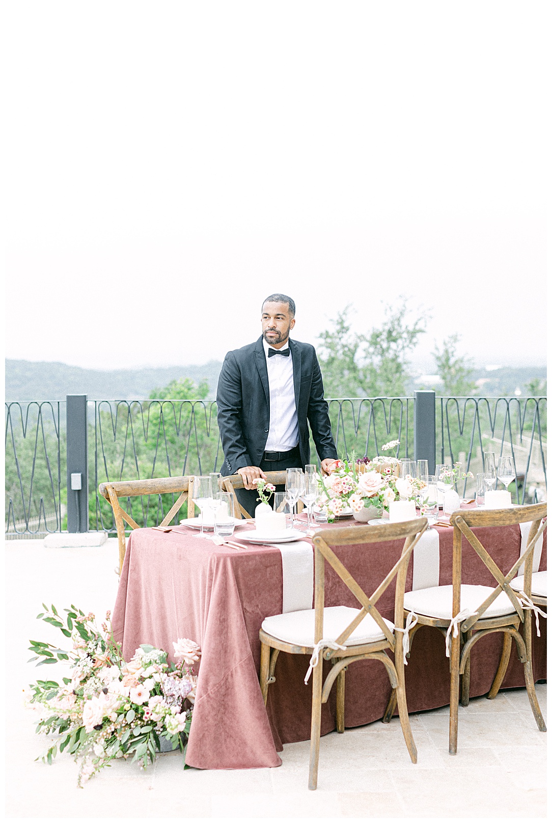 groom standing with mauve inspired table at wedding
