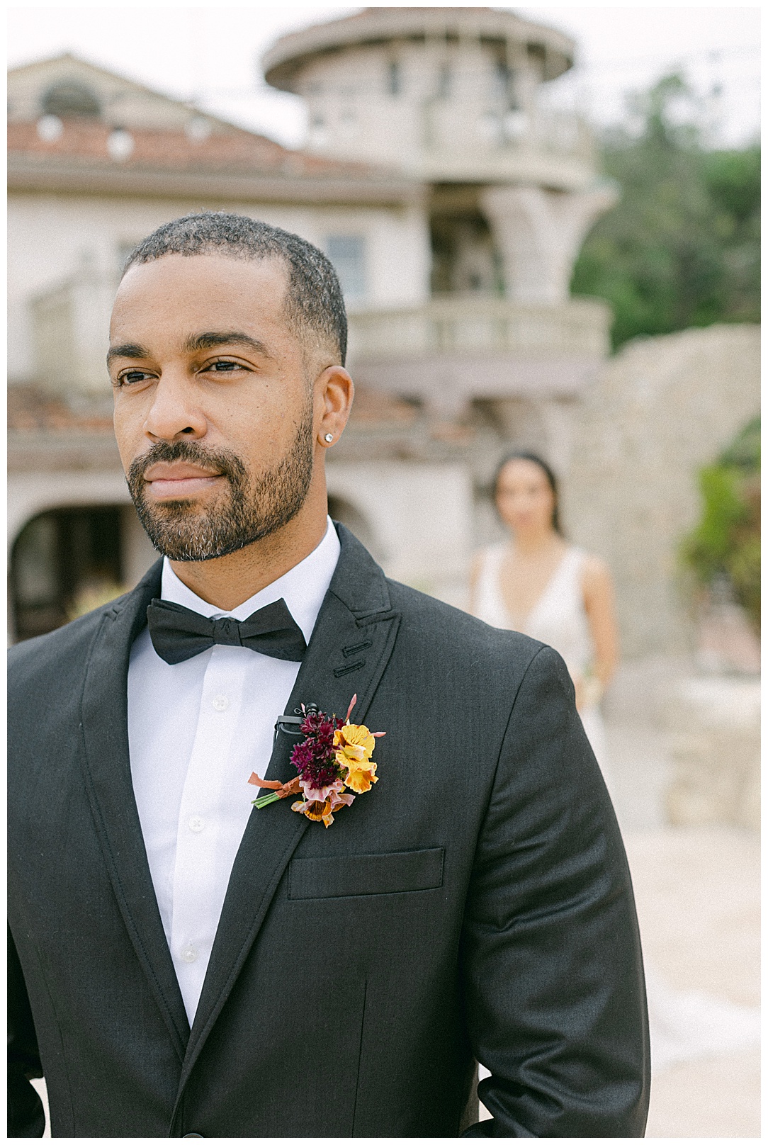 portrait of a groom with a bride in the background