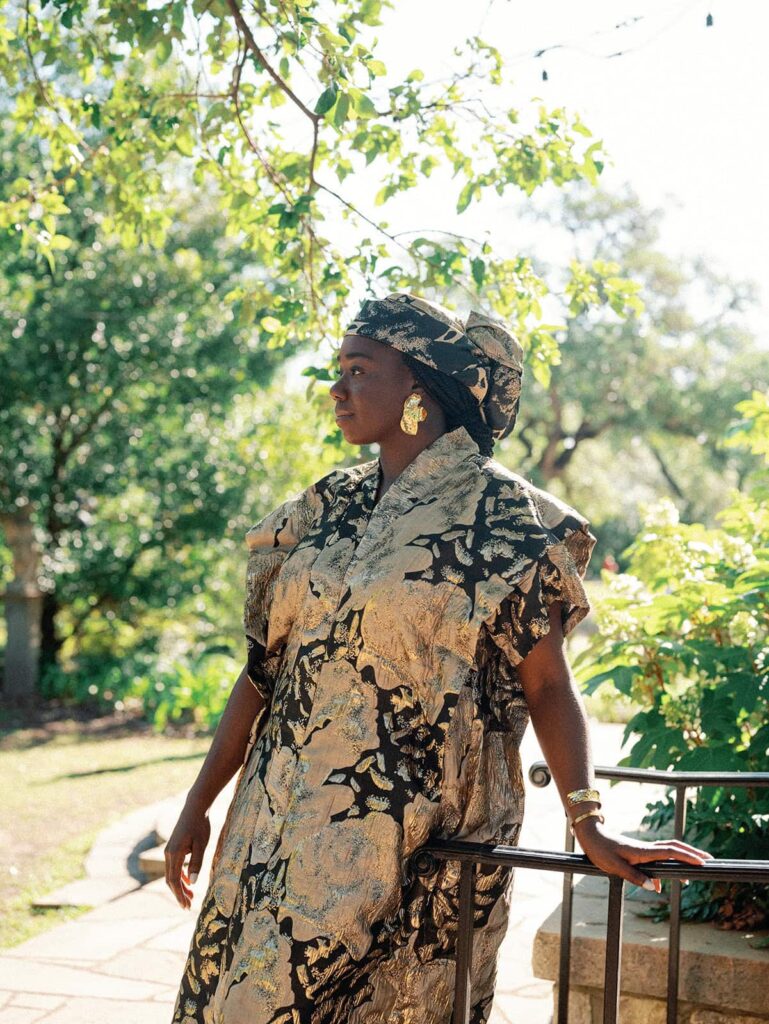 A woman poses leaning against a railing at Laguna Gloria for her Austin engagement photos.