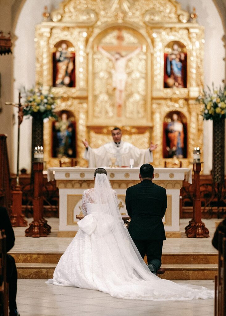 The bride and groom kneel before the altar at during their wedding ceremony.