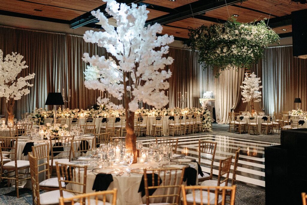 A cherry blossom tree stands in the middle of a table in front of a stripped dance floor at a Witte Museum wedidng.