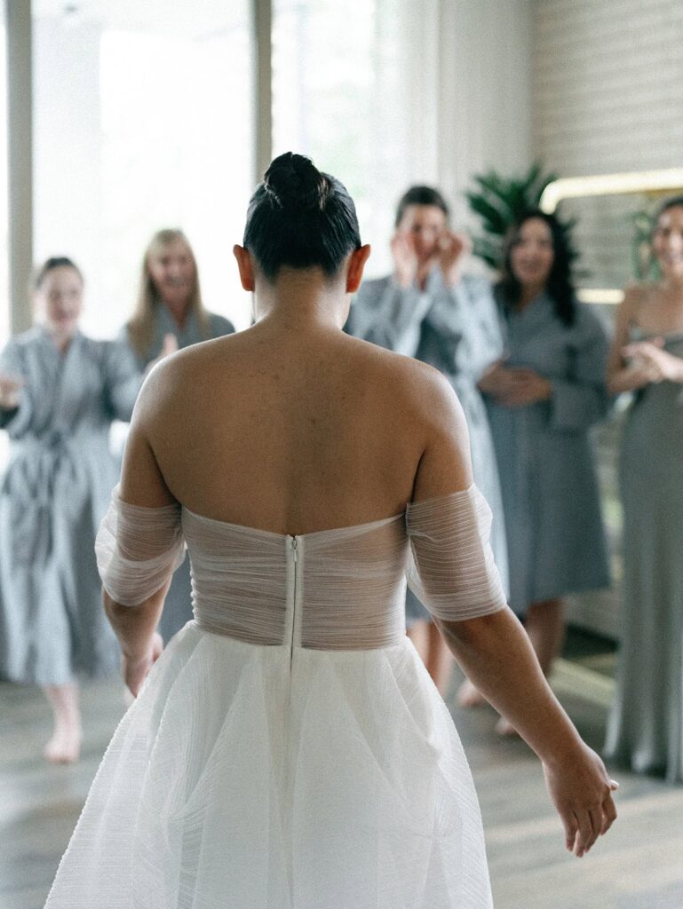 A bride walks towards her bridesmaids as they all cheer in excitement for her South Congress Hotel wedding look.